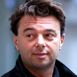 Close-up of Artistic Director Edward Hall, a man with short, tousled dark hair, wearing a dark jacket, looking slightly to the left with a neutral expression.