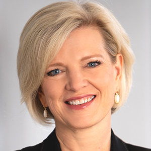 Professional headshot of a woman with short blonde hair and gold drop earrings, smiling.