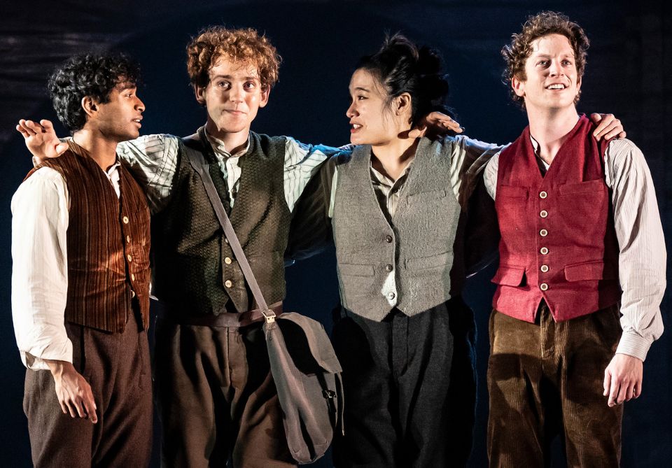 Standing from left to right with their arms around each other: actors playing the hobbits Pippin, Sam, Merry, and Frodo