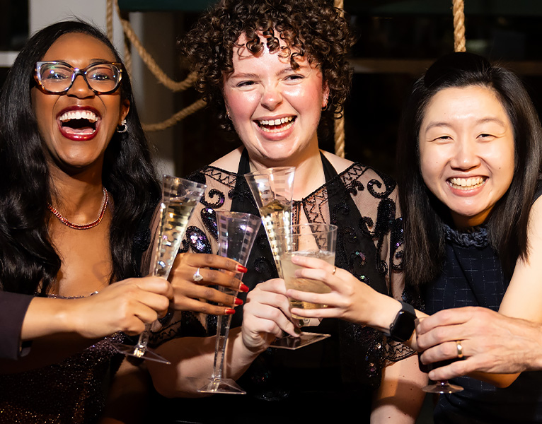 Three people smiling and toasting with champagne flutes.